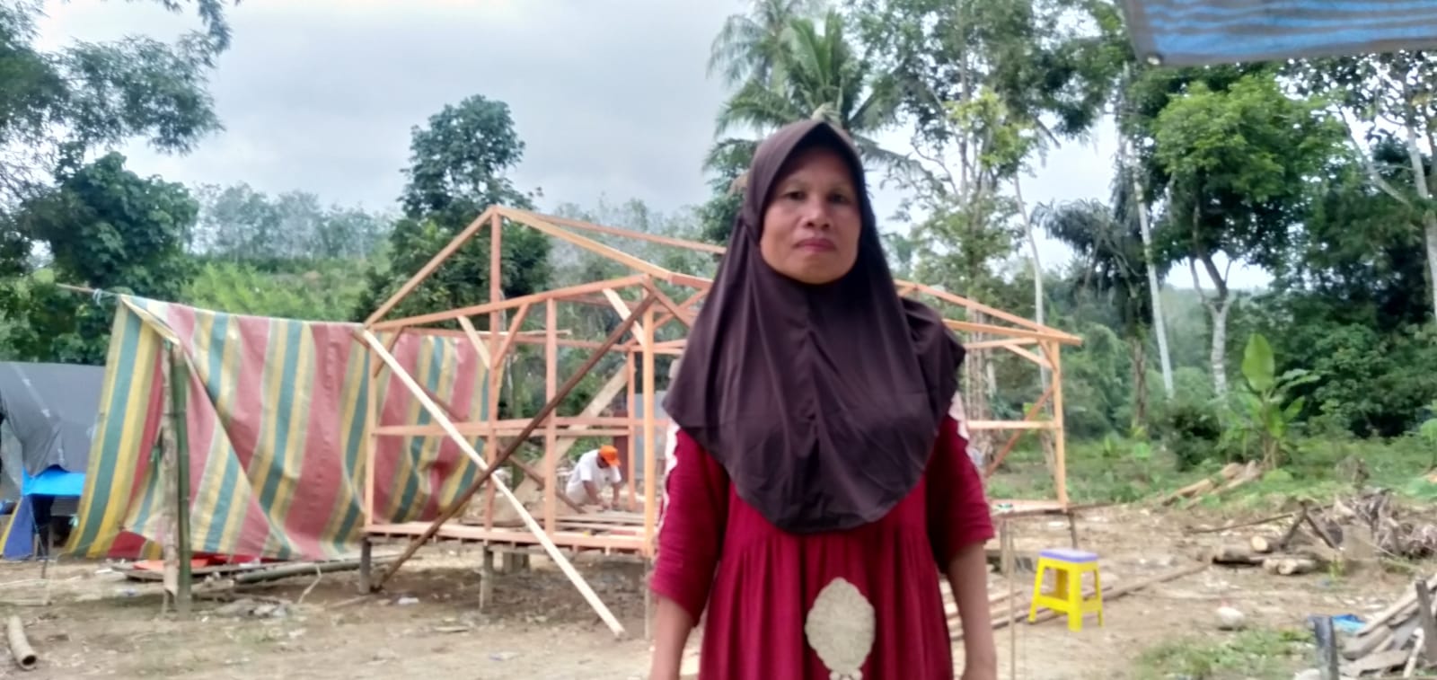 Foto : Ibu Farida bersama Rumah Senyum nya yang sedang dibangun.
